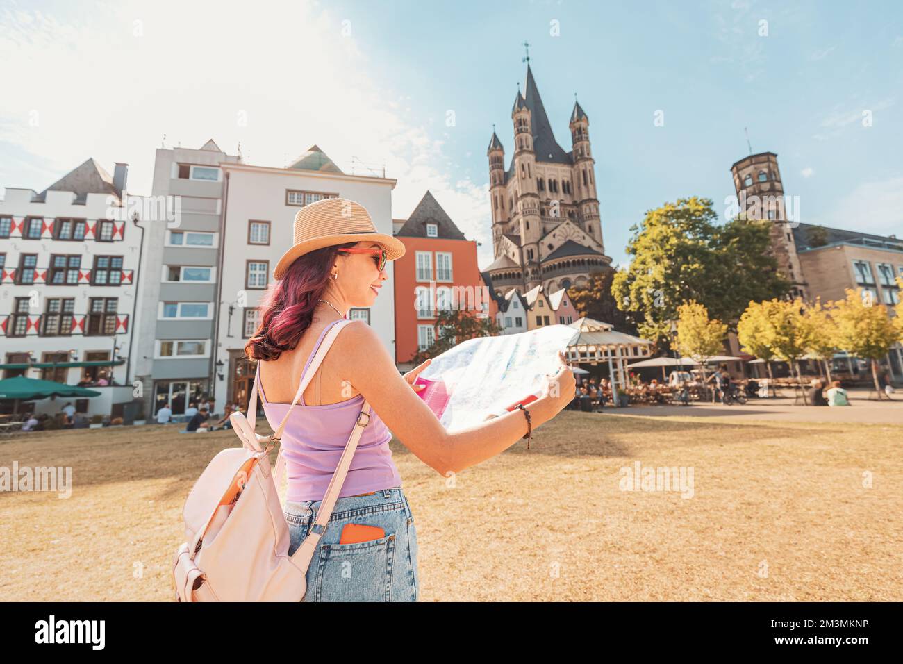 Happy tourist girl with maps, navigating and geolocating on the streets of an old European city of Koln Stock Photo