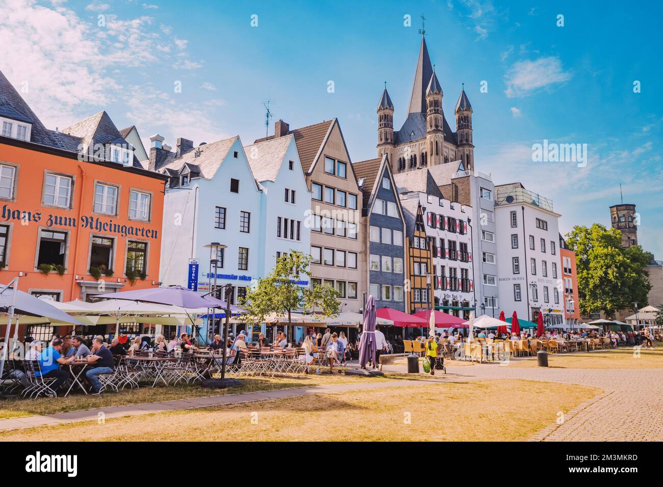 29 July 2022, Cologne, Germany: Fish market square with tourists resting in cafes, colorful houses and St. Martin Church in Koln. Travel and sightseei Stock Photo