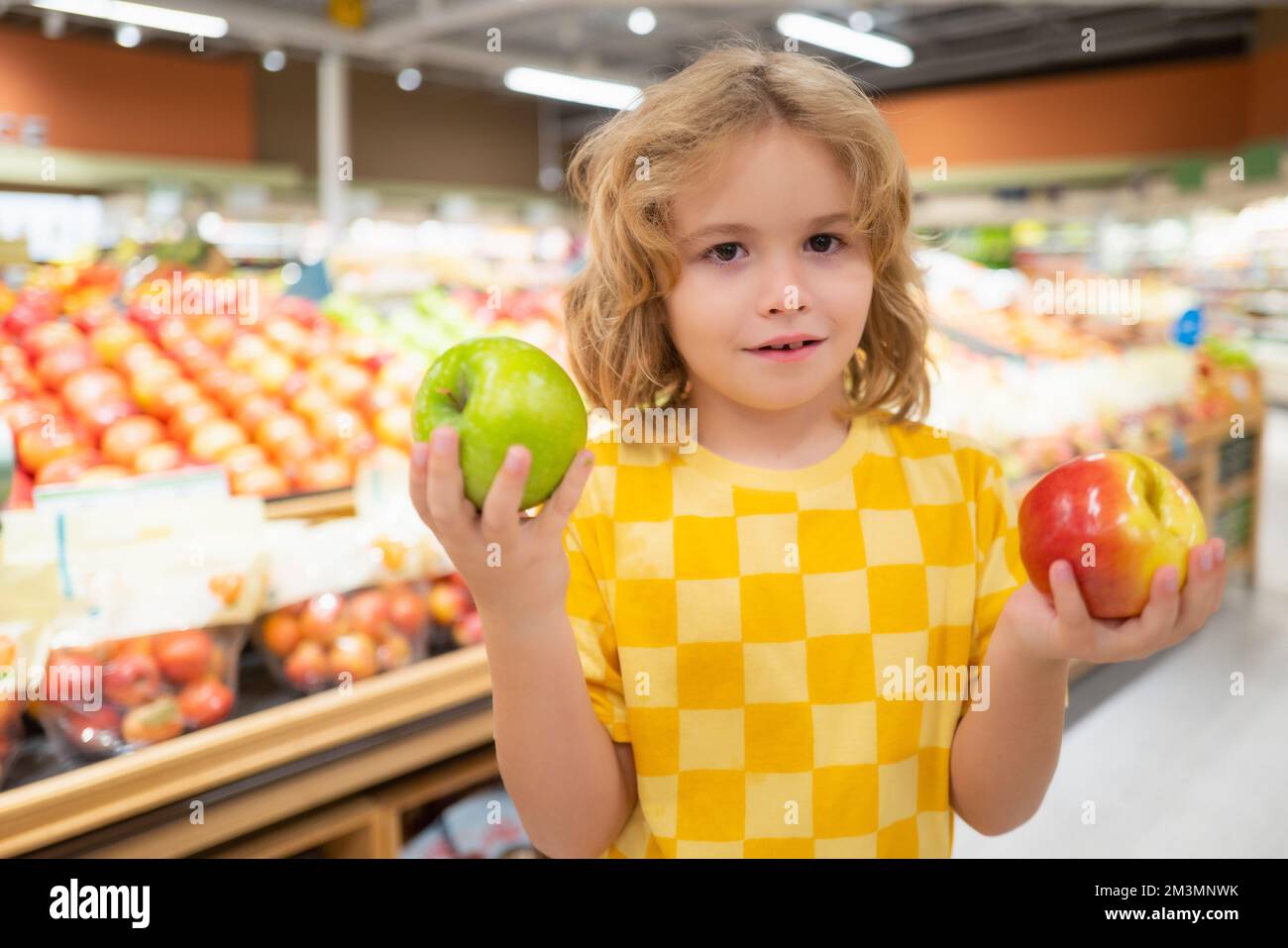 Child hold apple fruits at grocery store. Kid in a food store or a