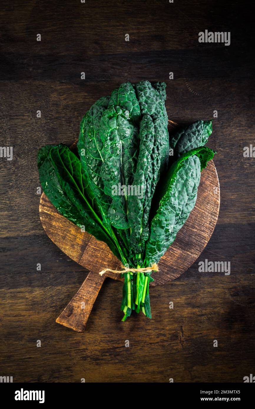 Palm kale, black cabbage - Cavolo nero black curly kale. Nero di Toscana (Brassica oleracea) on cutting board Stock Photo