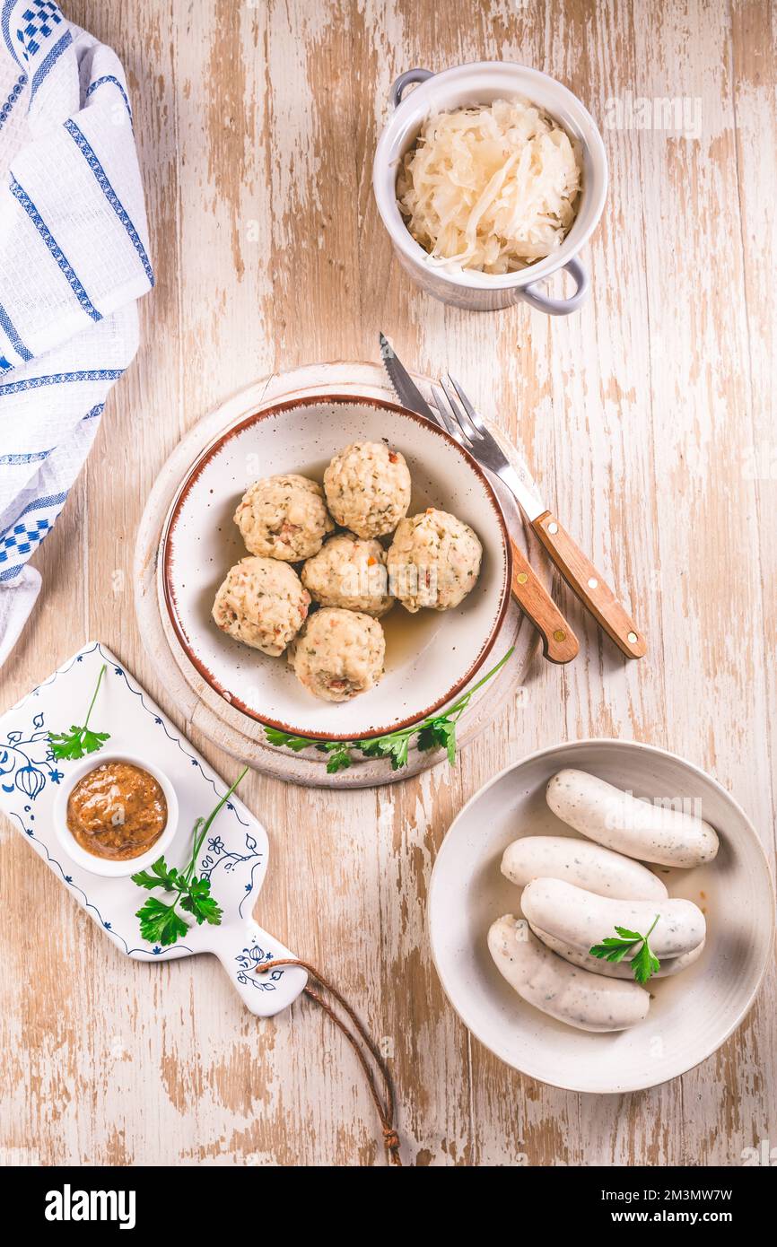 Traditional Bavarian cuisine - White veal sausage (Weisswurst) with pickled white cabbage (Sauerkraut) and bread dumplings with  Mustard Sauce Stock Photo