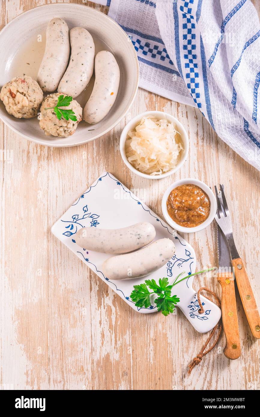 Traditional Bavarian cuisine - White veal sausage (Weisswurst) with pickled white cabbage (Sauerkraut) and bread dumplings with  Mustard Sauce Stock Photo