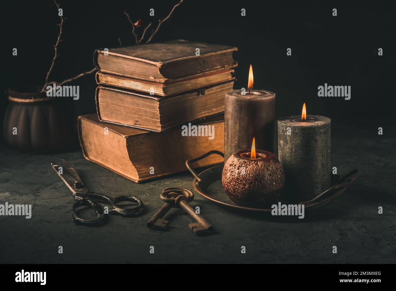 Pile of old antique books with candle and old rusty keys in vintage style on black background Stock Photo
