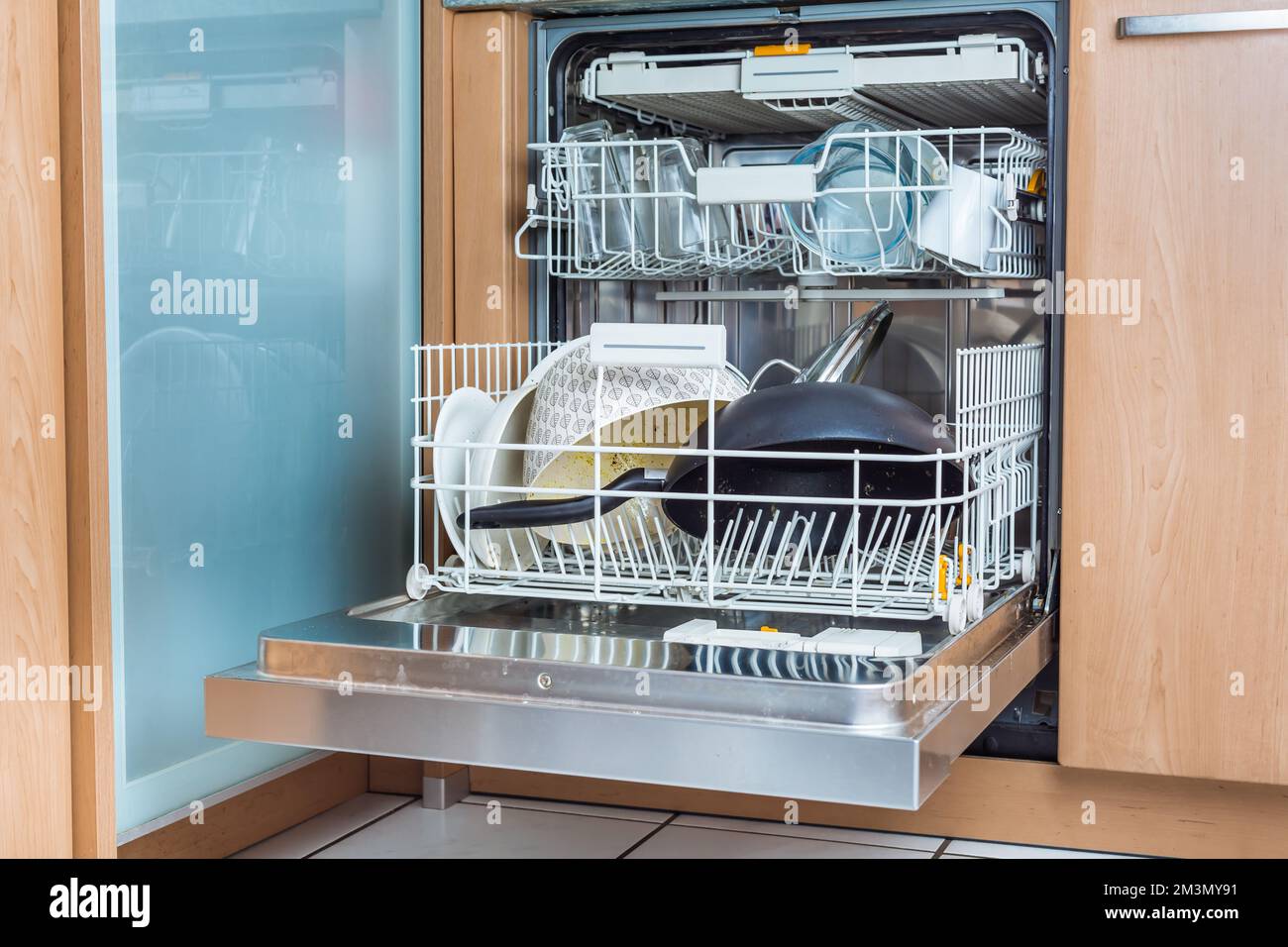 Open modern dishwasher with messy dishes  in the kitchen, built-in kitchen dish washing machine Stock Photo