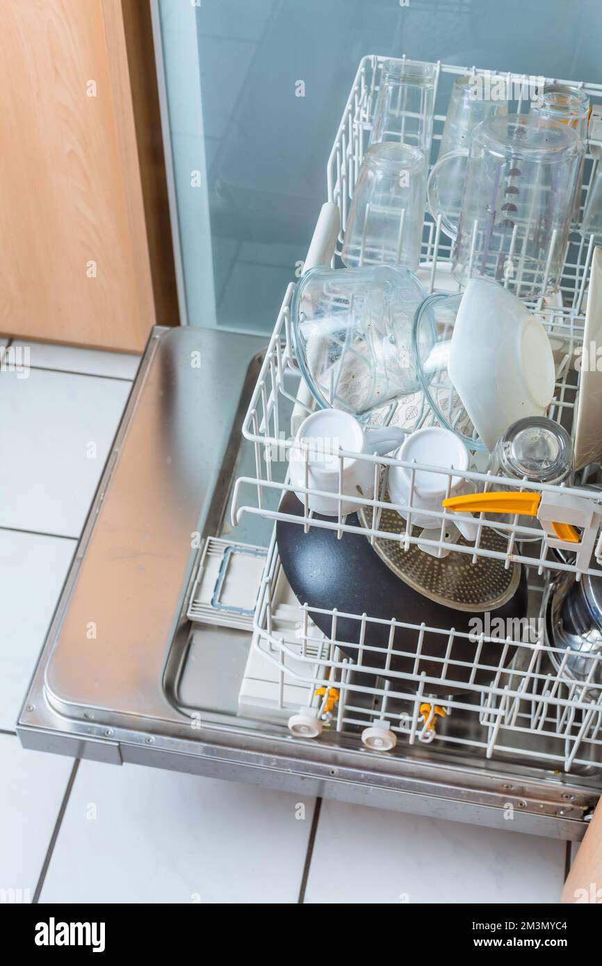 Open modern dishwasher with messy dishes  in the kitchen, built-in kitchen dish washing machine Stock Photo