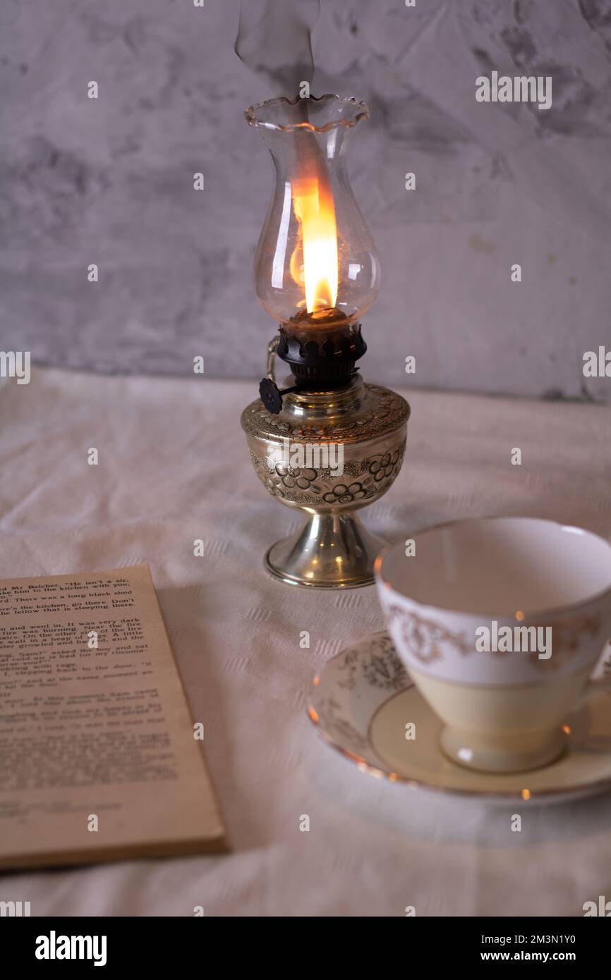 photo kerazine lamp empty cup and saucer old book on the table Stock Photo