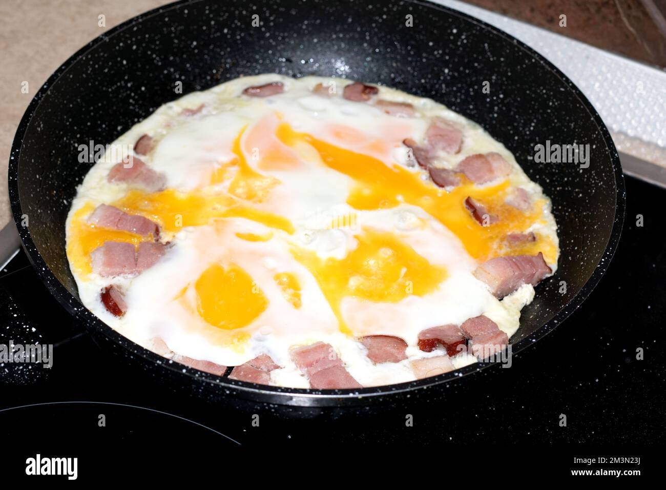 photo of eggs with bacon bits lying on the pan Stock Photo