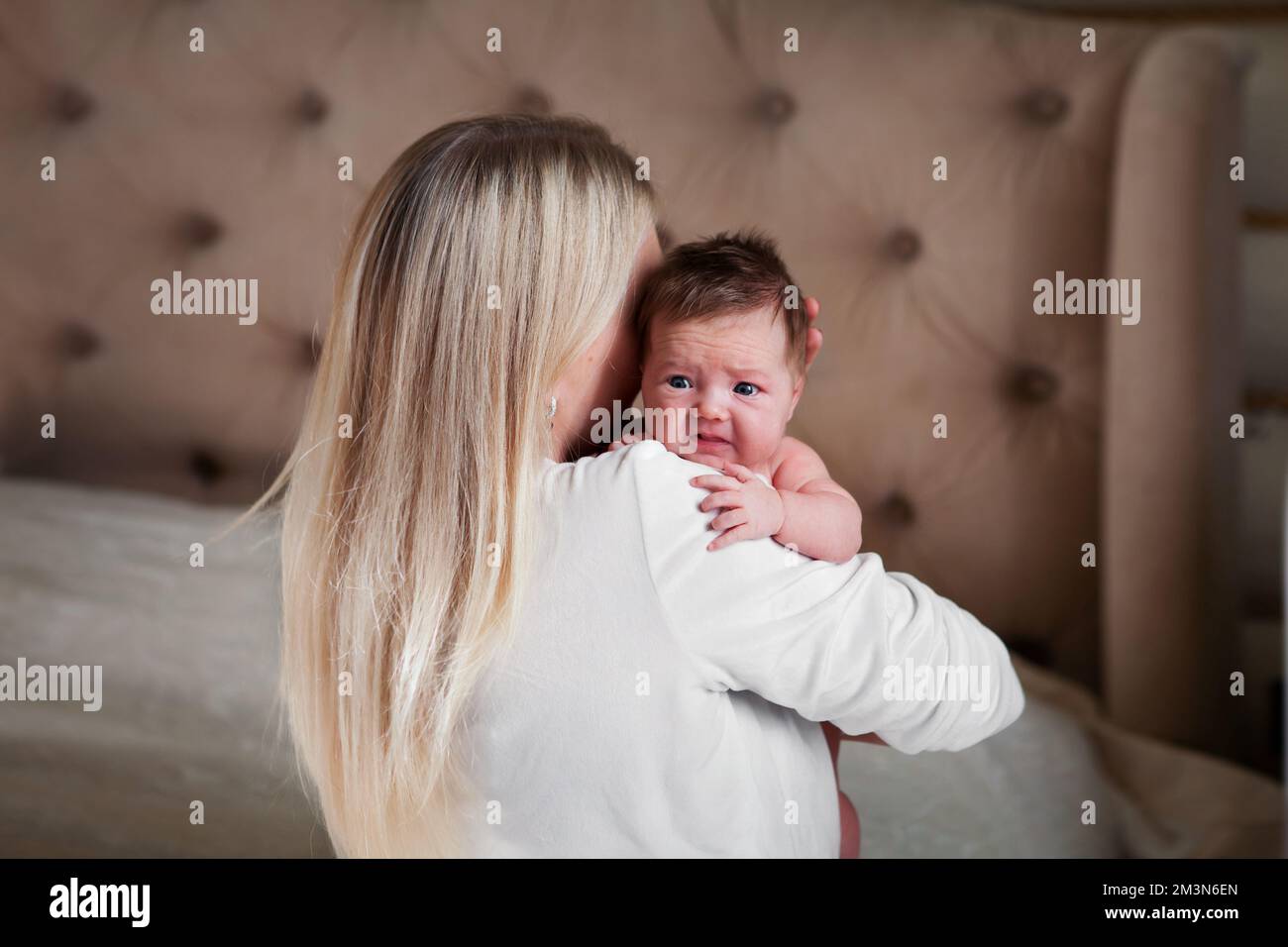 Mom holds scared, crying newborn baby in her arms, calms him down Stock Photo