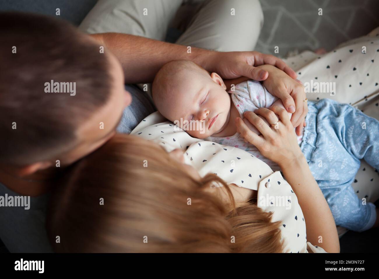 Portrait of sleeping newborn baby in arms of parents, mom and dad, top