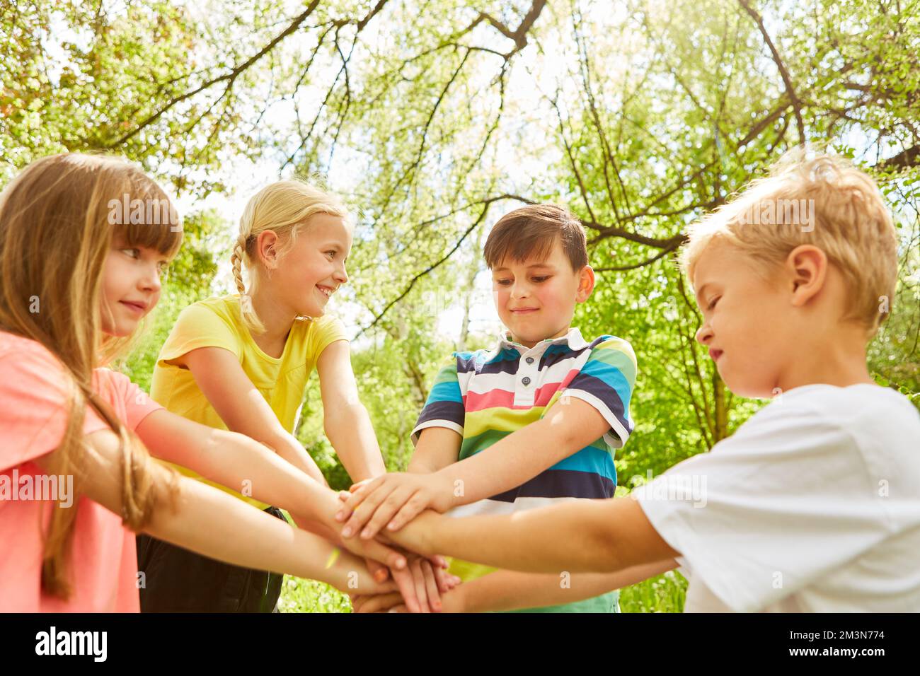 Happy multiracial elementary boys and girls stacking hands while ...