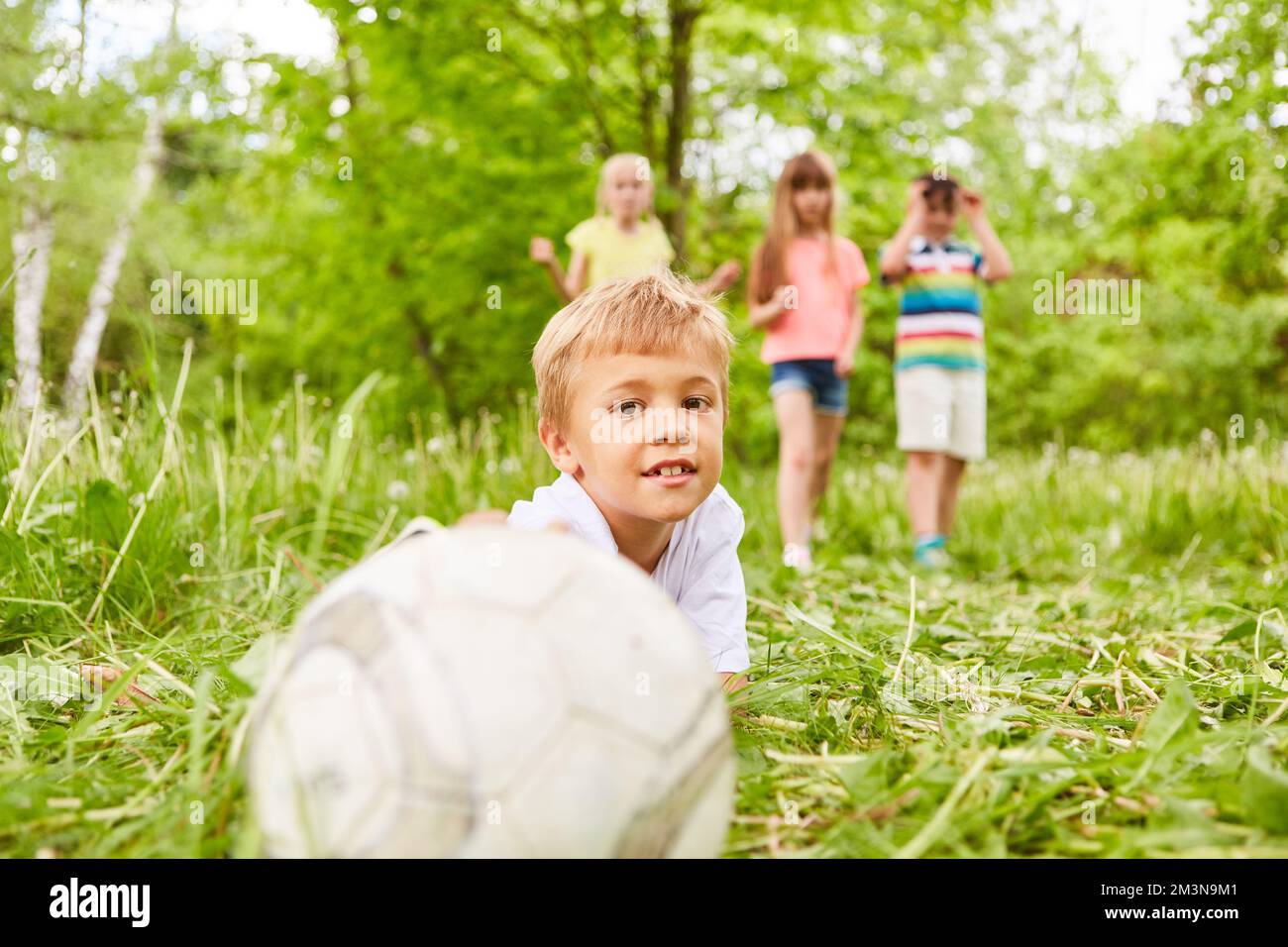 Portrait of boy touching soccer ball with friends in background at park
