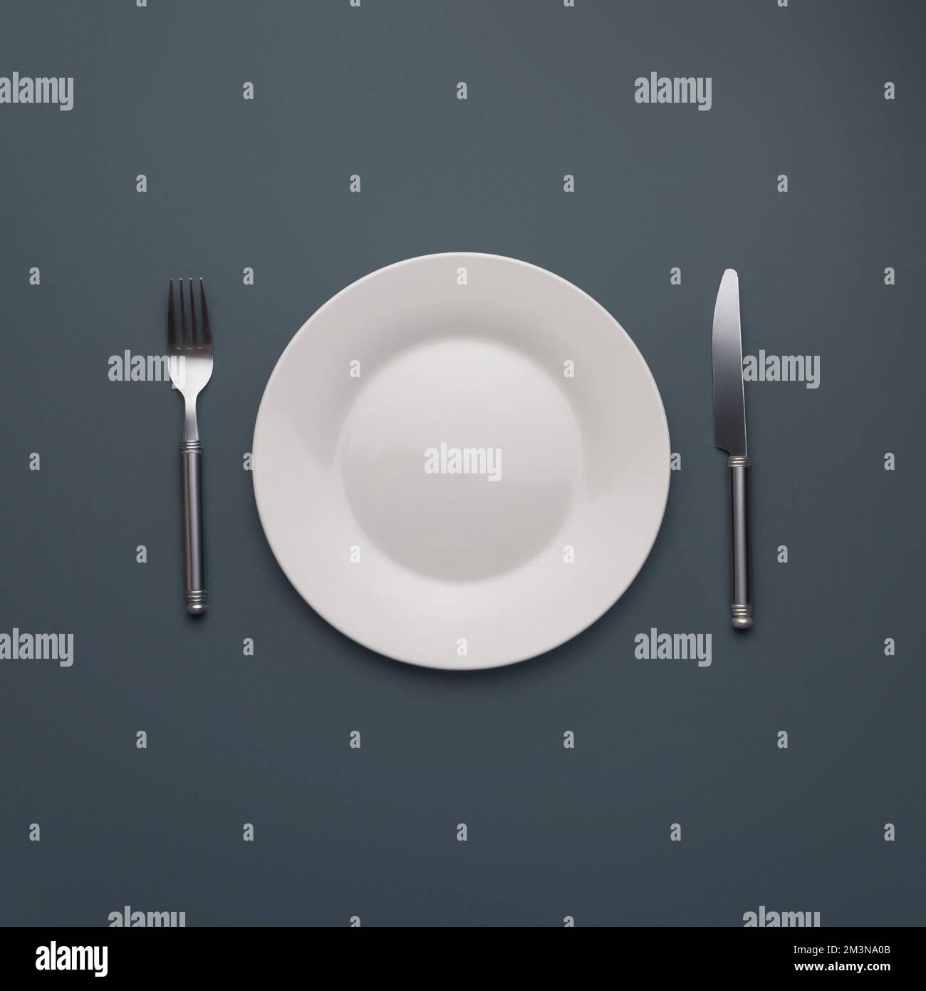 white empty plate with cutlery on dark gray background Stock Photo