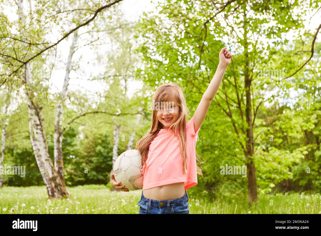 Portrait of smiling girl winning soccer game in park during summer holiday Stock Photo