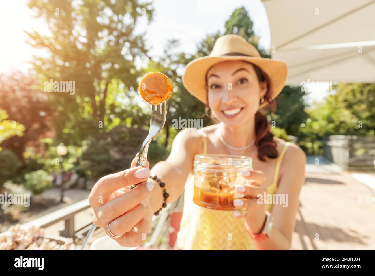 A happy girl eats an appetizing traditional German currywurst juicy sausage with seasonings at outdoor cafe Stock Photo