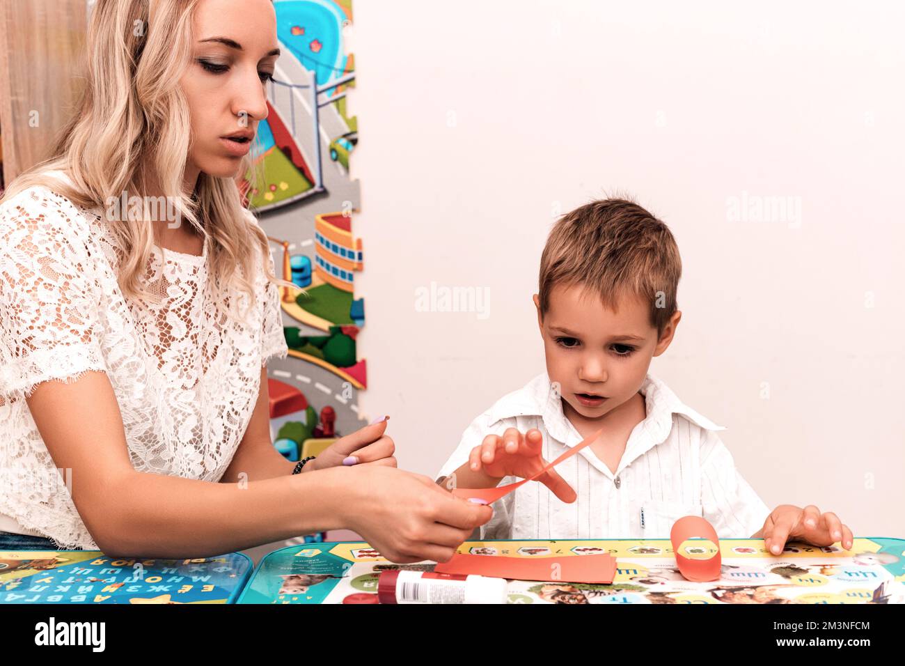 Mother and son sit and make a craft from paper and glue, lesson, handmade Stock Photo