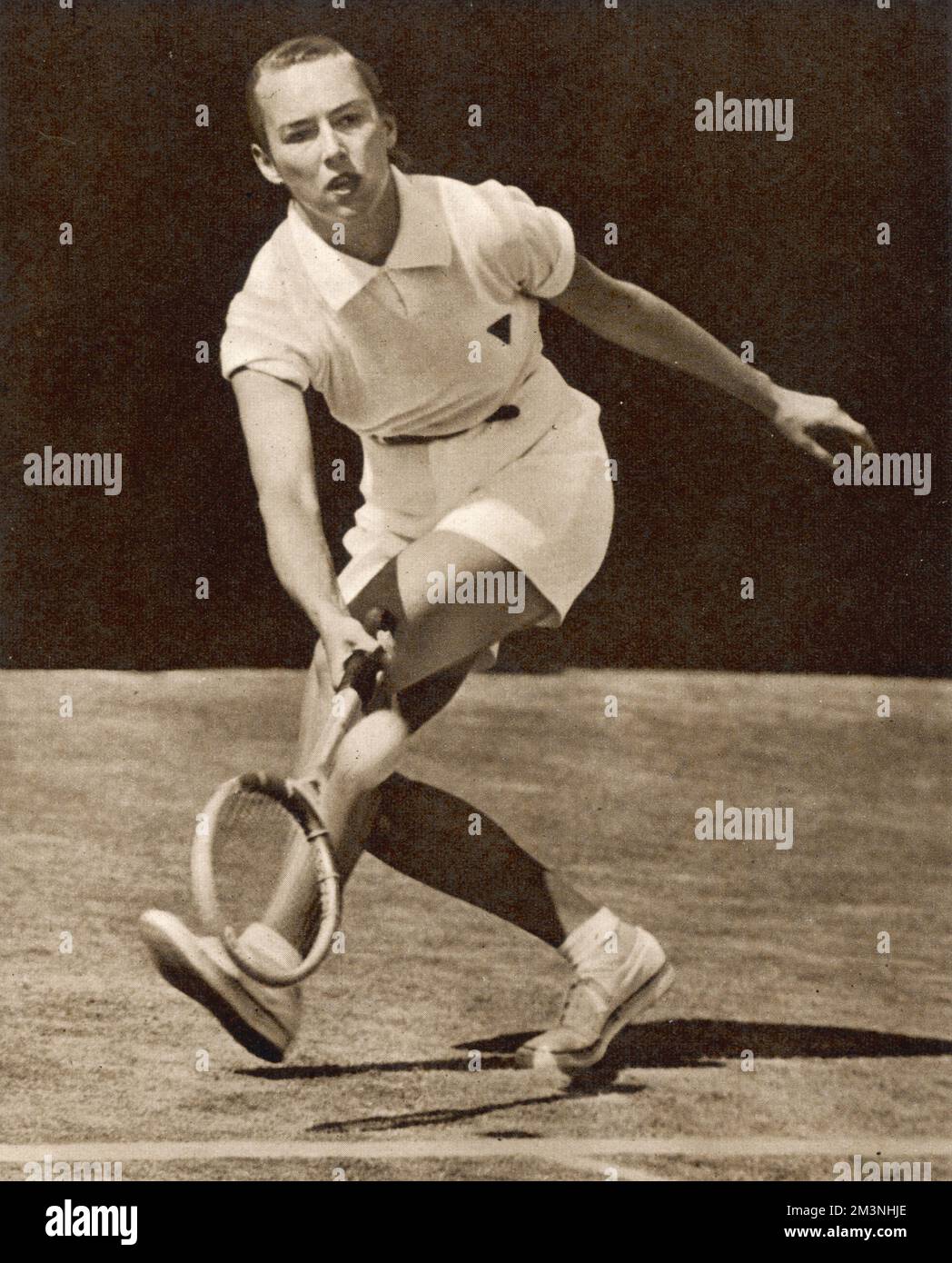 Gertrude Moran, American tennis player known as 'Gorgeous Gussie' by Wimbledon fans, due in part to the frilly pants designed by Teddy Tinling she wore in 1949.  Pictured here wearing boy's shorts with a red ribbon in her hair, on Court No. 2 at Wimbledon against Mrs Walter who she beat 3-6, 6-2, 6-3.     Date: 1949 Stock Photo