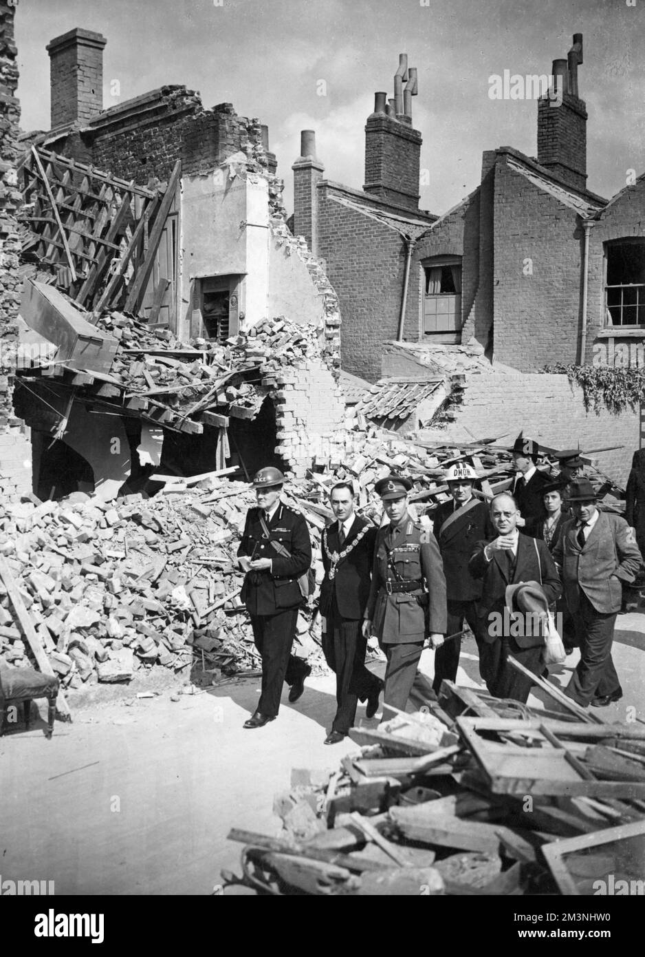 King George VI inspecting destroyed homes, part of the damage done by German air raids over London during the Blitz.       Date: 1940 Stock Photo