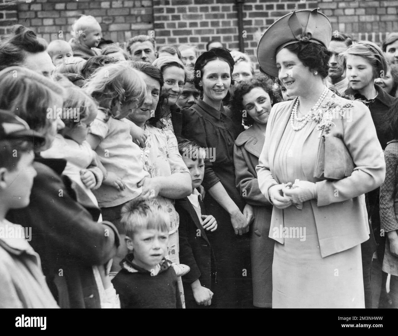 Queen Elizabeth, later the Queen Mother giving one of her gracious and charming smiles as she meets and sympathises with London residents in bomb damaged areas during the Blitz.       Date: 1940 Stock Photo