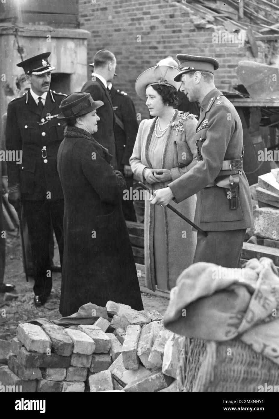 King George VI and Queen Elizabeth talking to Mrs Eals who was saved by taking cover in an Anderson shelter when her house was bombed during an air raid in September 1940.     Date: 1940 Stock Photo