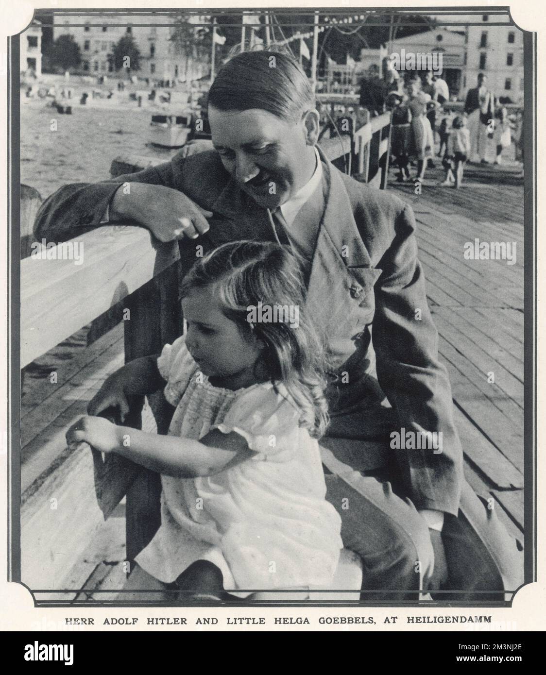 Herr Adolf Hitler and little Helga Goebbels at Heiligendamm. Hitler seated on a bench beside Helga, the eldest daugher of Joseph Goebbels, (aged 3 in this photograph) at the seaside resort of Heiligendamm on the Baltic.     Date: 1935 Stock Photo