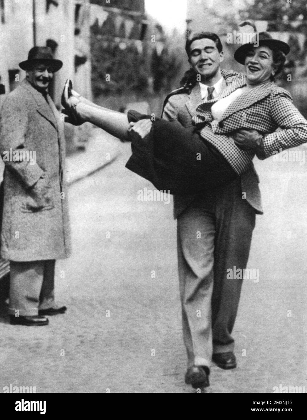Prince Franz Josef Hohenlohe carries his mother, Princess Stephanie Hohenlohe, with Count Woracziczky watching from a safe distance. Despite her Jewish heritage, Stephanie was a close friend of Adolf Hitler and other members of the Nazi party. She was declared an 'honorary Aryan' by Goring and Himmler and became a Nazi spy, appreciated for her intelligence and good advice.     Date: 1937 Stock Photo