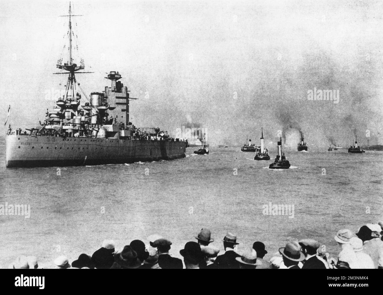 British battleship HMS Rodney, at this point one of the most powerful battleships in the world, leaving the River Mersey, in charge of a flotilla of tugs, for Portsmouth, watched by spectators.     Date: 1927 Stock Photo