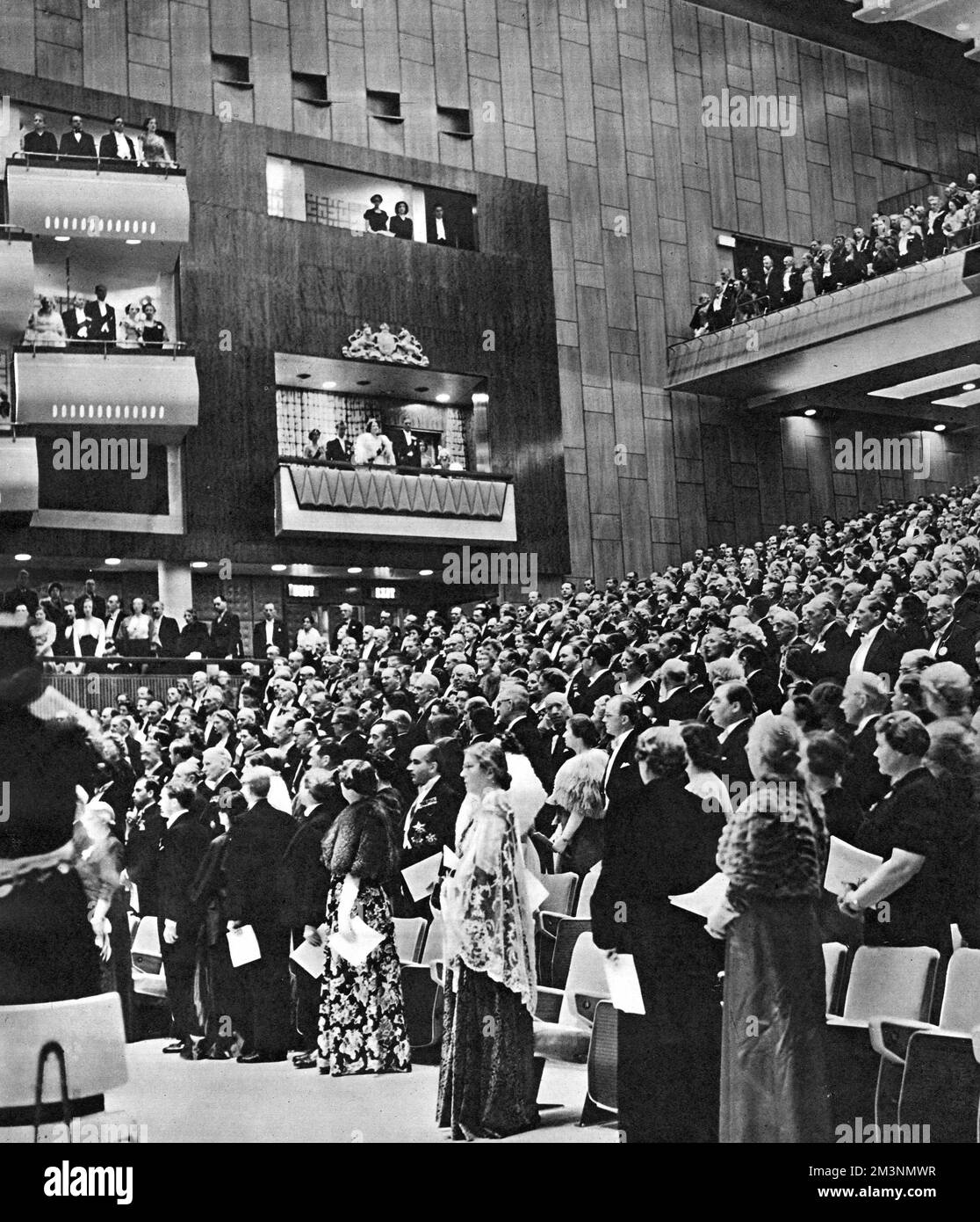 Scene at the royal opening of the new Royal Festival Hall, on the South Bank, London, with a full auditorium, and members of the royal family in the royal box -- King George VI and Queen Elizabeth, Princess Elizabeth and the Duke of Edinburgh, and Princess Margaret.  After the National Anthem came a service of dedication, with a short address by the Archbishop of Canterbury, then an inaugural concert with suitably patriotic British music.      Date: 3 May 1951 Stock Photo