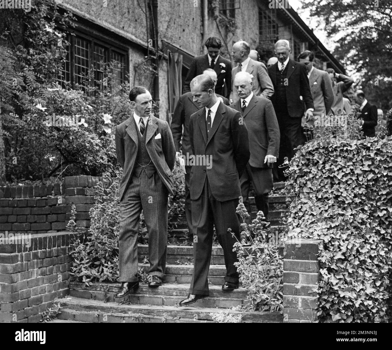 Prince Philip, Duke of Edinburgh (born 1921), attending a garden party at the White House, Woodford Green in aid of the Essex  Playing Fields.  Photograph shows the Duke walking down to lunch with Mr Nigel Capel-Cure, chairman of the Essex branch of the National Playing Fields Association of which Prince Philip is president.     Date: 1949 Stock Photo