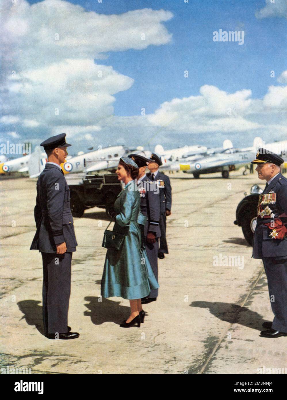 Queen Elizabeth II on her tour of inspection during the RAF Coronation Review at Odiham, Hampshire in July 1953.  She is pictured talking to Observer Commander, E. J. B. Irving of the Royal Observer Corps, and behind her is Air/Cdre.G. D. Stephenson, the Static Parade Commander.  On the right is the Air Chief Marshal Sir William Dickson, Chief of Air Staff, and in the background, Wing Commander D. I. Benham, Static Parade Adjutant.  In the picture can be seen a Land Rover of a type often used by the Queen and other members of the Royal family for parades of this nature.     Date: 1953 Stock Photo