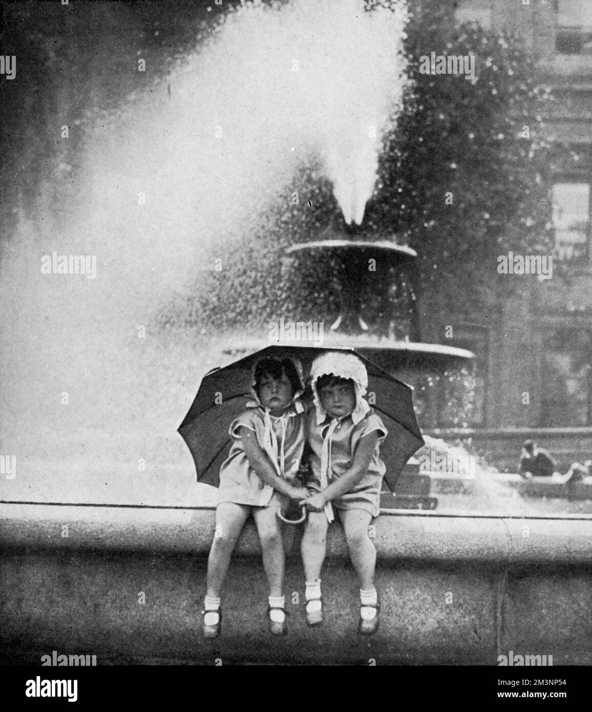 Two little girls cool off during a heat in the fountains of Trafalgar Square.     Date: 1929 Stock Photo