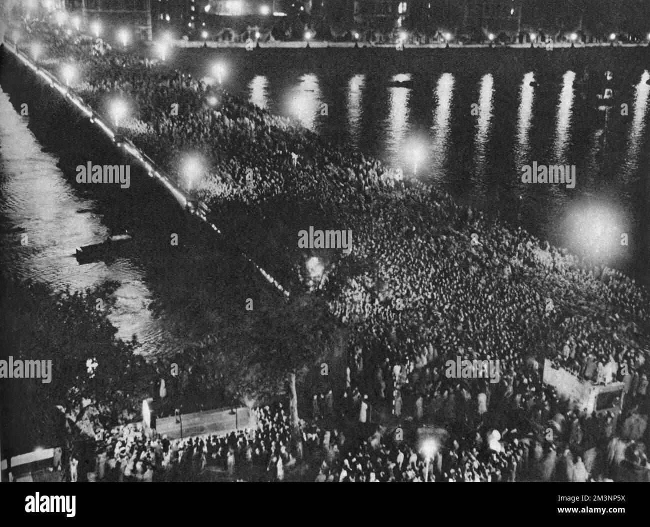 Westminster Bridge entirely covered in crowds of people enjoying a firework display on Coronation night.     Date: 1953 Stock Photo