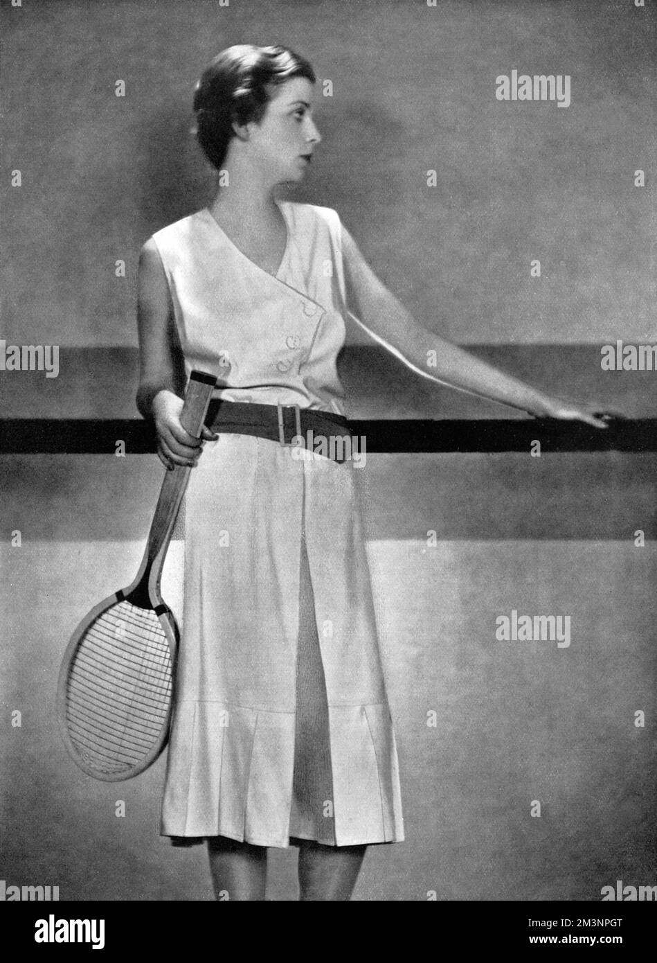 An exclusive Bystander photograph showing the designer, Elsa Schiparelli's practical but stylish jupe-pantalon tennis dress in light white woollen weave with a waist belt of orange coloured tussore.  The style which feature culottes or a divided skirt was adopted by the Spanish tennis star Lili de Alvarez who wore Schiaparelli's designs at Wimbledon in 1931, causing a sensation.     Date: 1930 Stock Photo