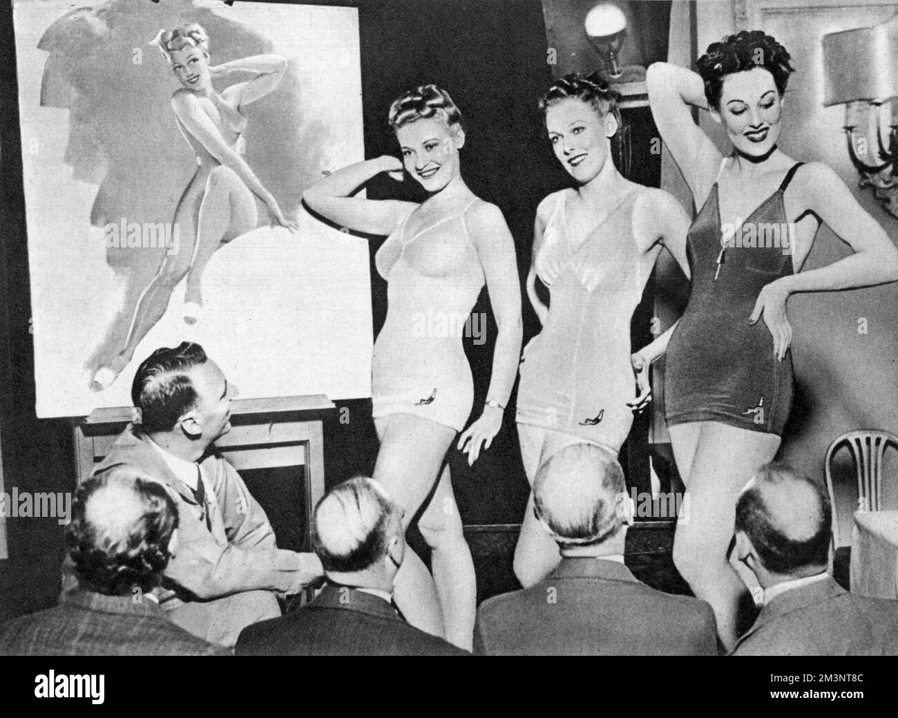 Pin-up artist Merlin Enabnit posing with some of his real-life models to promote his series of pin-ups featuring in The Sketch magazine in 1940.  An American artist, Merlin, used the new air-brush technique to paint extremely curvaceous and pneumatic girls.  His pin-up series in The Sketch was followed by the Lovelies of David Wright.  The editorial accompanying this piece compares the pin-ups of Merlin with those by Raphael Kirchner published in The Sketch during World War I.       Date: 1940 Stock Photo