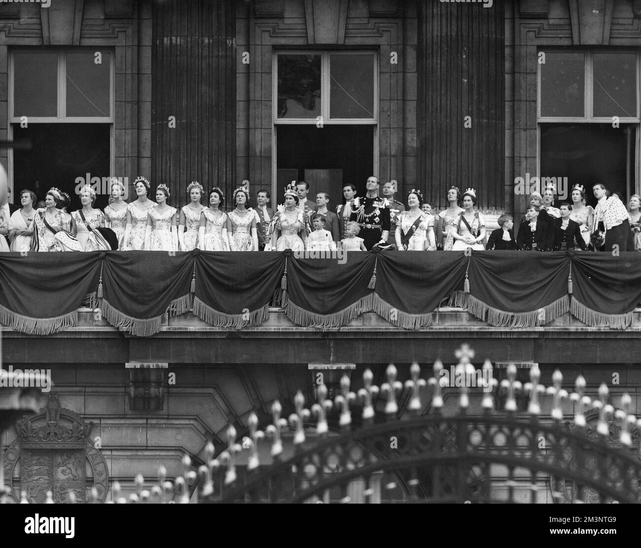 The Queen wearing the imperial crown, members of the royal family, and maids of honour, on the balcony at the palace for the fly-past of the RAF following her Coronation on 2nd June 1953.     Date: 1953 Stock Photo