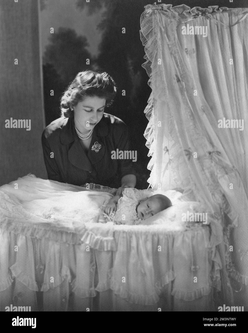 Princess Elizabeth (Queen Elizabeth II) gazes down at her firstborn child, Prince Charles (Prince of Wales) lying in his cradle.       Date: 1948 Stock Photo