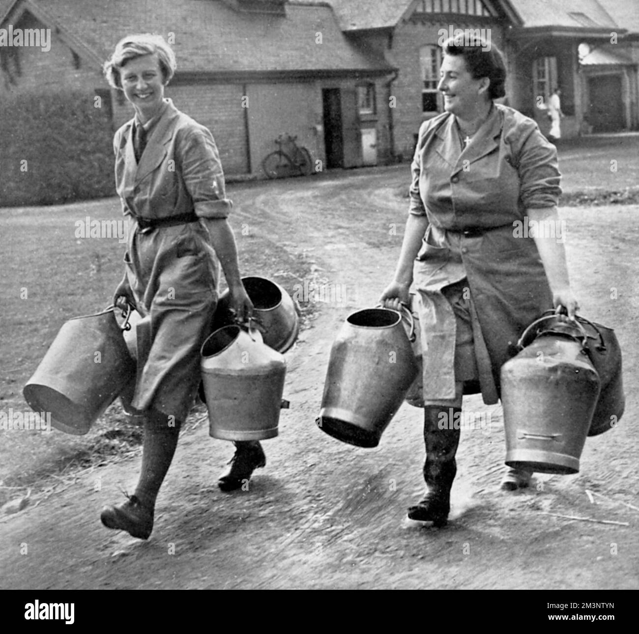 Two women at the Cheshire School of Agriculture pictured carrying milk ...