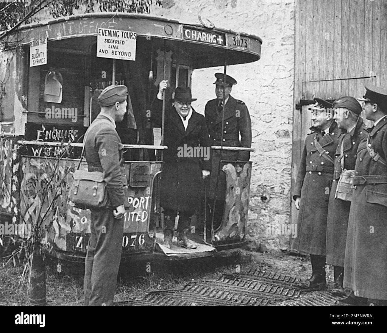 Sir Kingsley Wood (1881 - 1943), Secretary of State for Air pictured during a tour of the R.A.F. in France, the first British Defence Minister to visit British Forces overseas in 1939.  He is seen before a bus which has been converted for office use and is adorned with humorous slogans and signs.  Behind him is Air Vice-Marshal Peirse; on the right are Air Vice-Marshal P.H.L. Playfair, Air Officer Commanding the RAF in France and wo staff officers - Group-Captain A. H. Wann and Air-Commodore J. C. Quinnell.       Date: 1939 Stock Photo