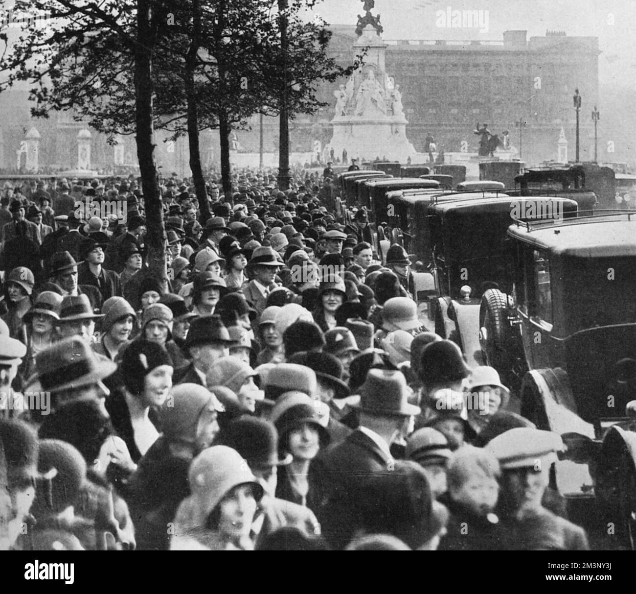 A familiar sight in central London during the Season - a long line of cars snaking its way up the Mall towards Buckingham Palace.  Inside are debutantes and other ladies who are to be presented at court, all of them coming under the scrutiny of the crowds who gather to watch.       Date: 1930 Stock Photo