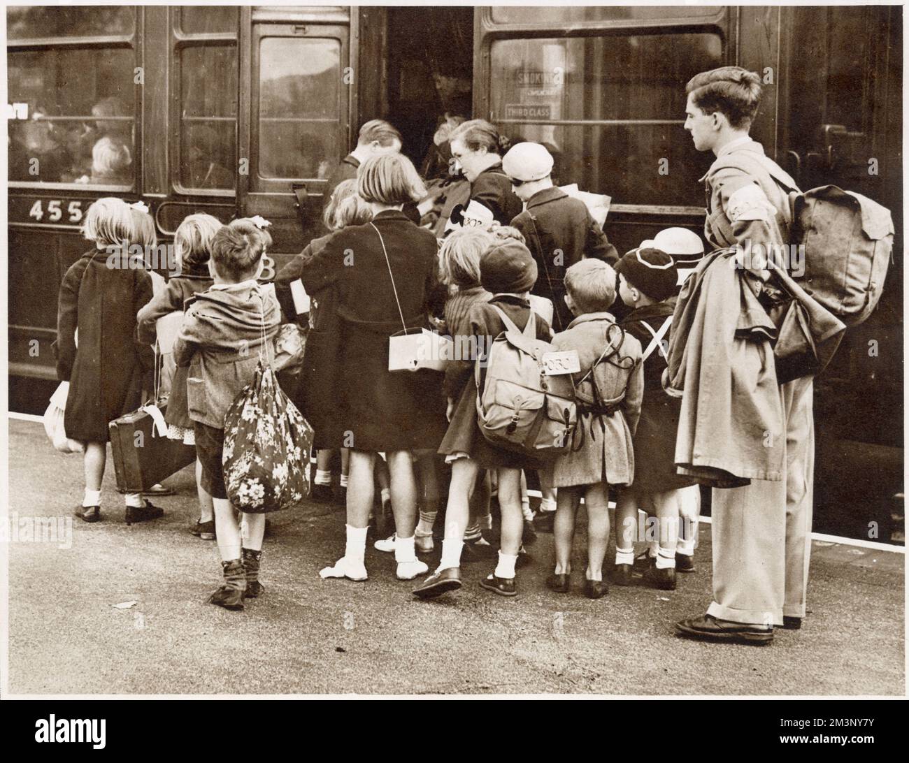 London's children evacuated at the beginning of World War Two: a first wave of 400000 children went on 1st September 1939, in the charge of 22000 teachers. Here a party is seen boarding a train at a main line station in the suburbs of London, equipped with gas masks and carrying their belongings in bags and haversacks. Stock Photo