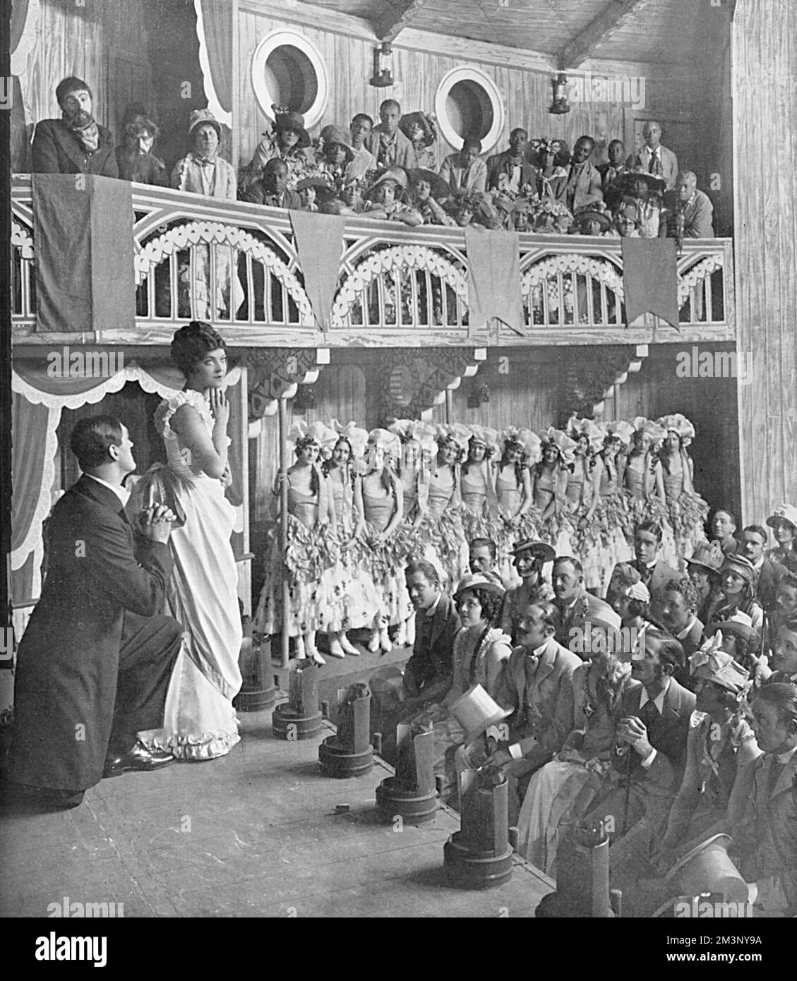 The auditorium and stage of the 'Cotton Blossom', as Captain Andy's show boat is called in the musical, Show Boat.  Howett Worster and Edith Day playing the third act of the 'Parson's Bride' to the mixed company of black and white, of the levee town of Natchez.  Show Boat was originally written by Edna Ferber and adapted by Oscar Hammerstein as a stage musical with the black actor, Paul Robeson starring as Joe.     Date: 1928 Stock Photo