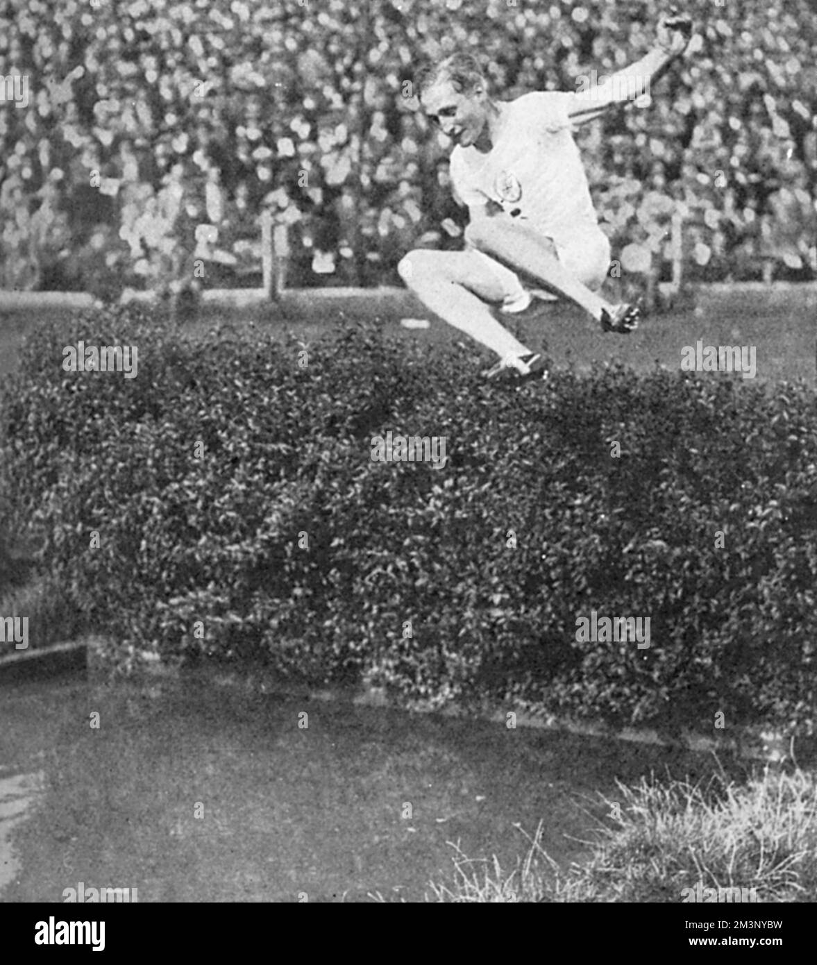 400 metres hurdles gold medallist, Lord Burghley, at the water jump in the steeplechase at an athletics meeting at Stamford Bridge, shortly after his win at the 1928 Amsterdam Olympic Games.  David George Brownlow Cecil, 6th Marquess of Exeter (1905 - 1981), Lord Burghley was an athlete, sports official and Conservative party politician   As an athlete, Burghley was a very keen practitioner who placed matchboxes on hurdles and practised knocking over the matchboxes with his lead foot without touching the hurdle. In 1927, his final year at Magdalene College, Cambridge, he amazed colleagues by s Stock Photo