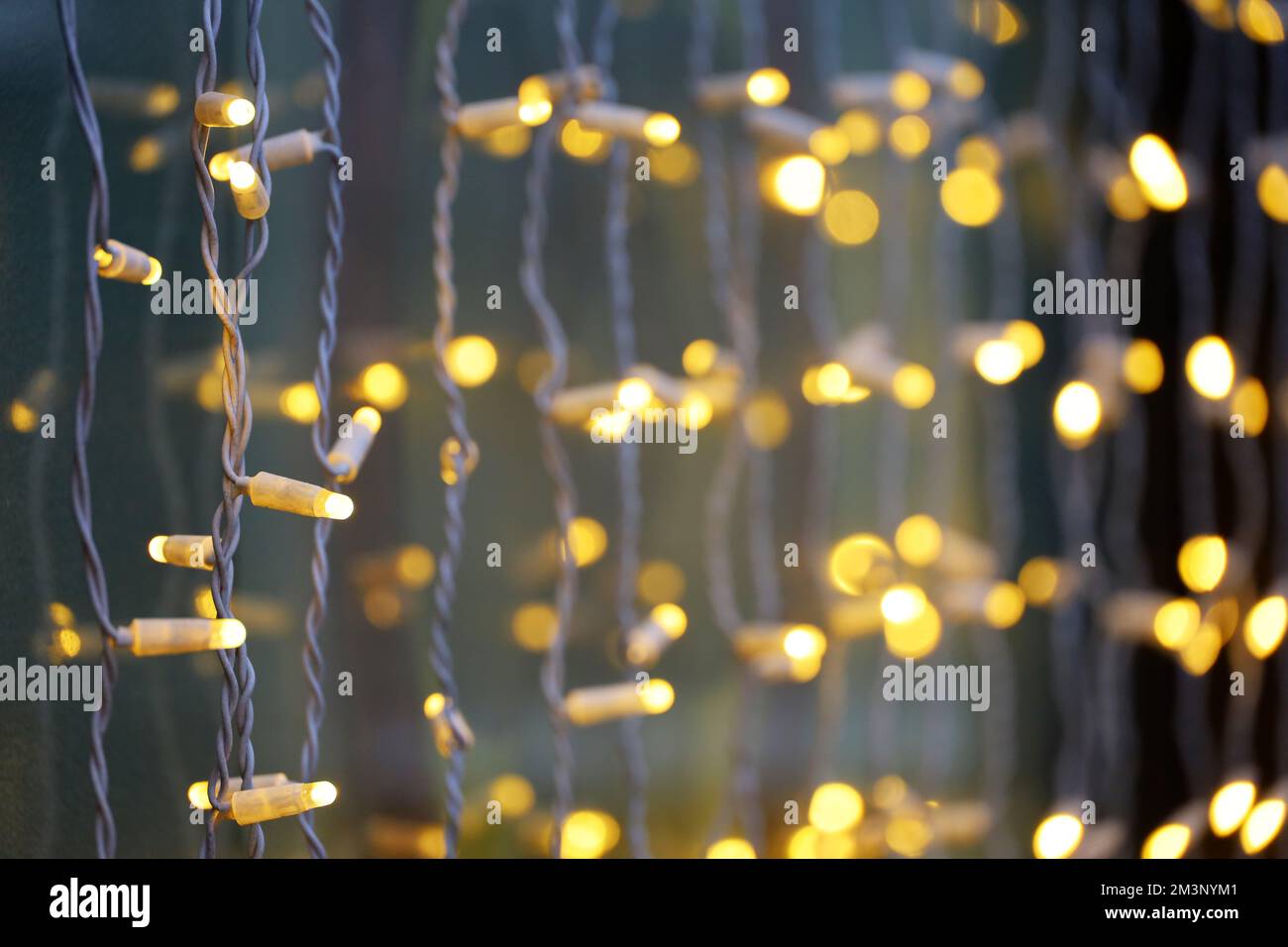 Festive lights on electric garlands. Christmas decorations, New Year illumination in window on city street Stock Photo
