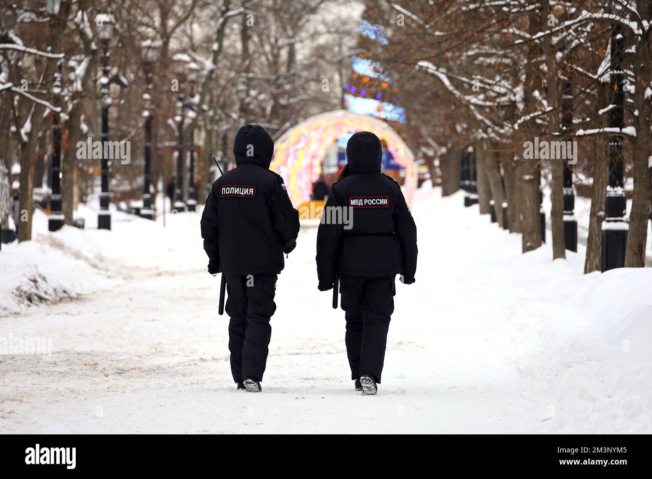 Russian police officers patrol a city street in Moscow on background of New Year decorations. Translation of inscriptions on the human backs: 'Police' Stock Photo