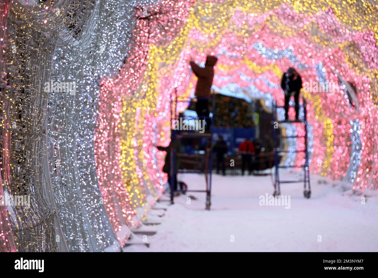 New Year ornaments on city street, workers decorating illuminated arch in winter city. Preparing for Christmas holidays Stock Photo