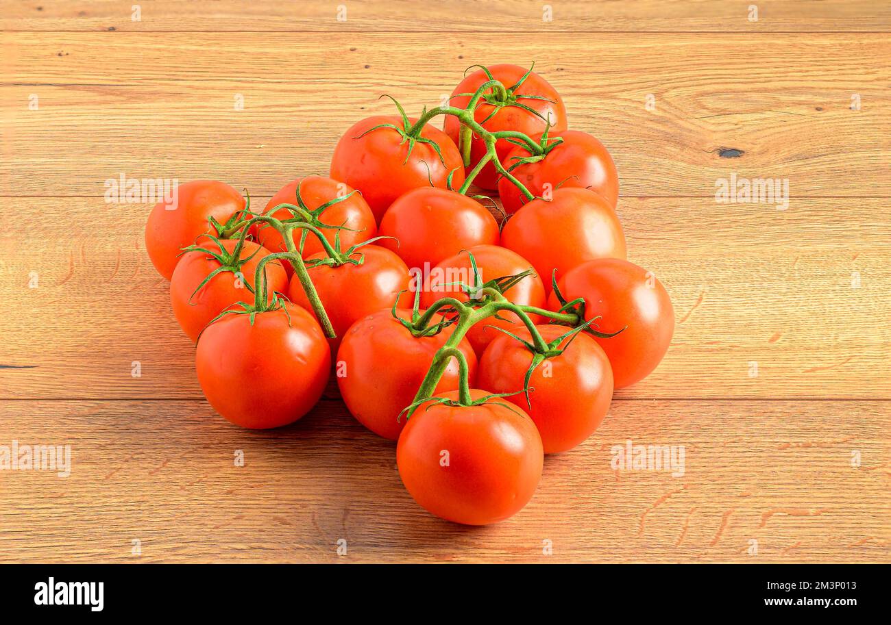 A closeup shot of juicy red tomatoes on vines on a wooden table Stock ...
