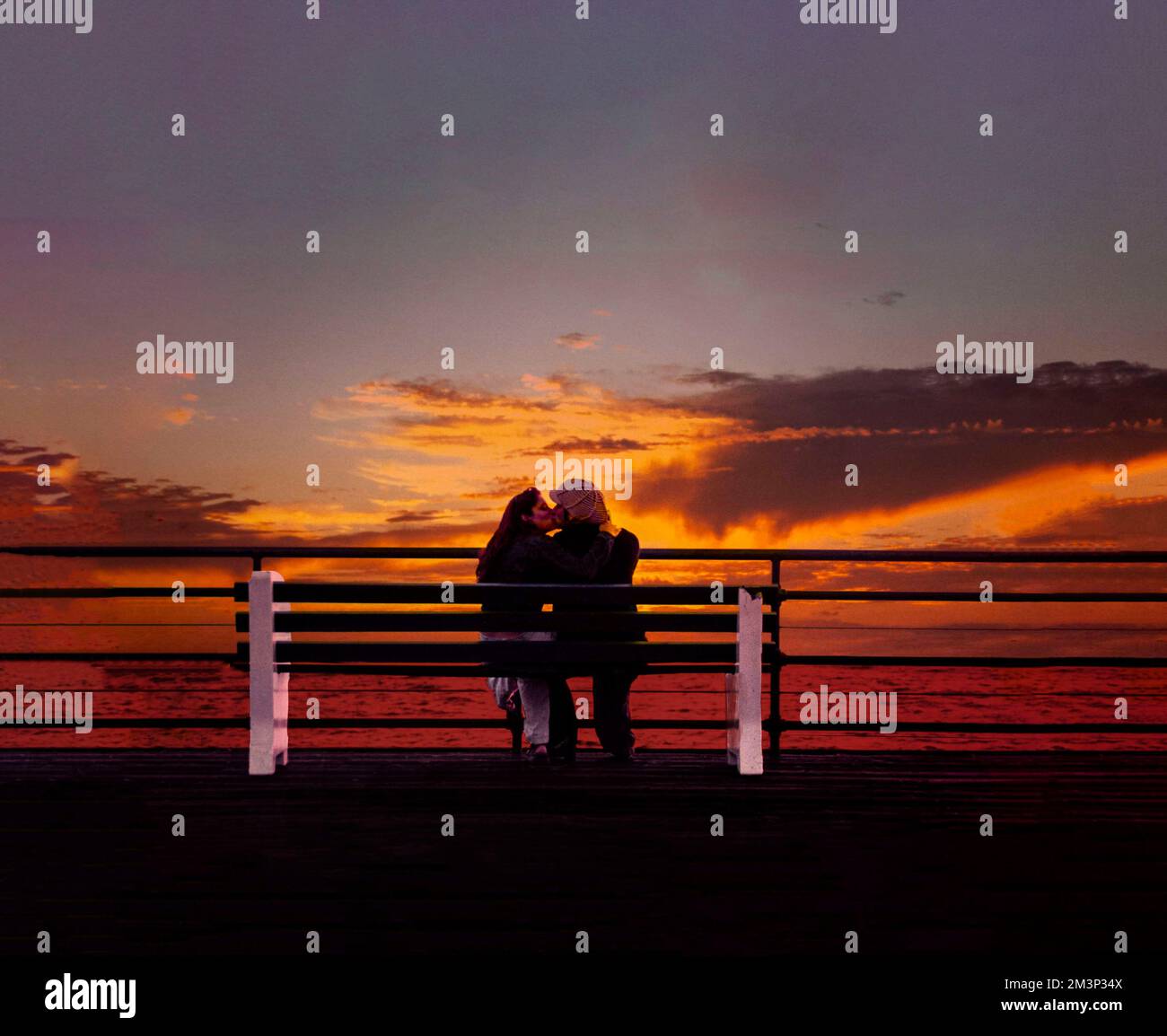 Silhouette of couple kissing at sunset on a bench on the Santa Monica Pier for Valentine's Day Stock Photo