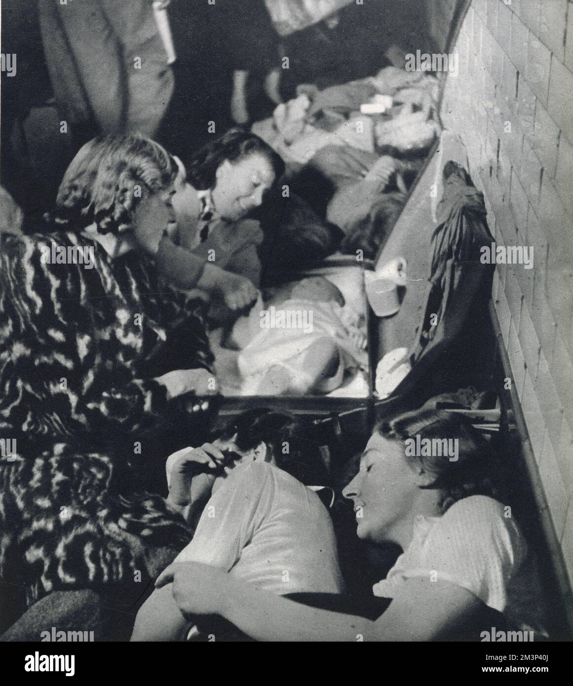 German bombing campaign against Britain between September 1940 and May 1941 mainly targeting London and industrial places. Photograph showing women sleeping in cramped conditions in a underground tube station and mother watching over a baby in a suit-case.      Date: October 1940 Stock Photo