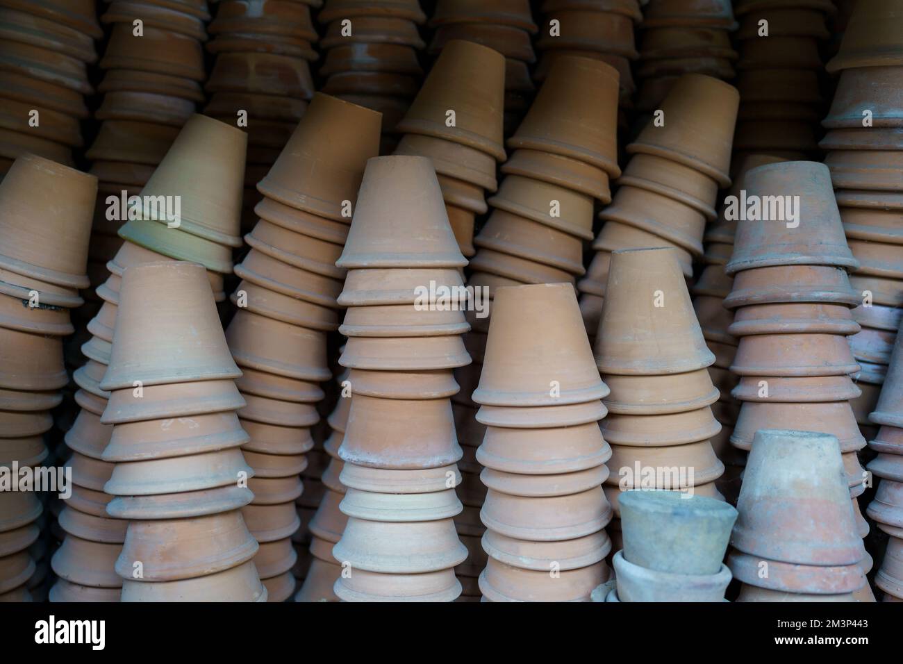 Closeup of stacks of old used weathered terra cotta flower pots in gardening shed Stock Photo