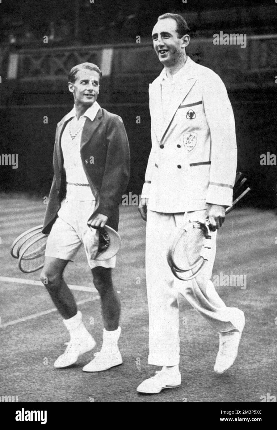 Henry Wilfred 'Bunny' Austin (1906-2000), looks up at the towering frame of his 6 ft 7 inche opponent, Lyttelton Rogers of Ireland, coming out to play the first match at Wimbledon in the Coronation Year Lawn Tennis Championships.  Austin won the four-set match, 3-6, 8-6, 6-1, 6-2.     Date: 1937 Stock Photo