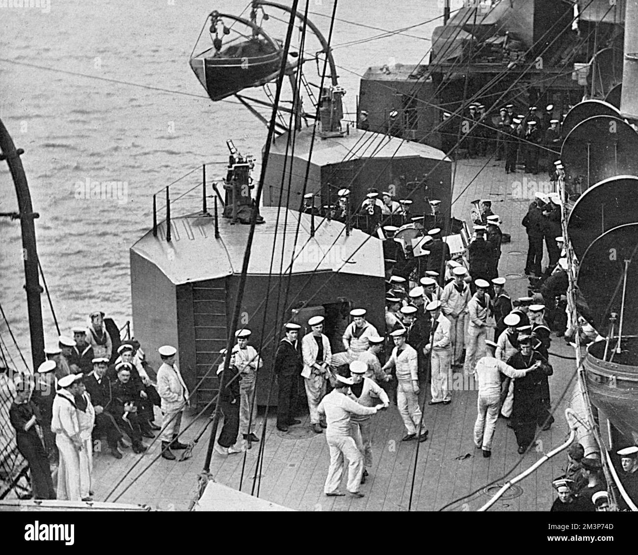 Jack's leisure hour in war-time enlivened by the strains of the ship's band.  British sailors on an unidentified ship enjoy relax on board by dancing.      Date: 1916 Stock Photo